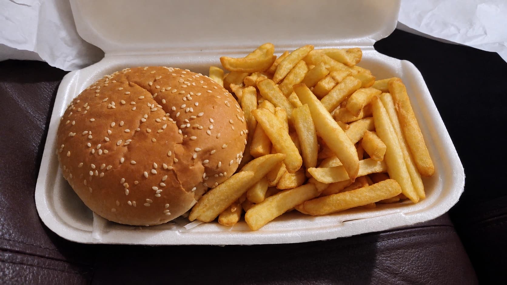 A burger and chips in a takeaway box